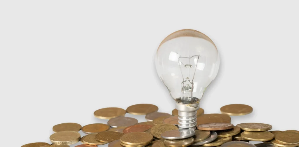 Sebuah bohlam di atas tumpukan koin.