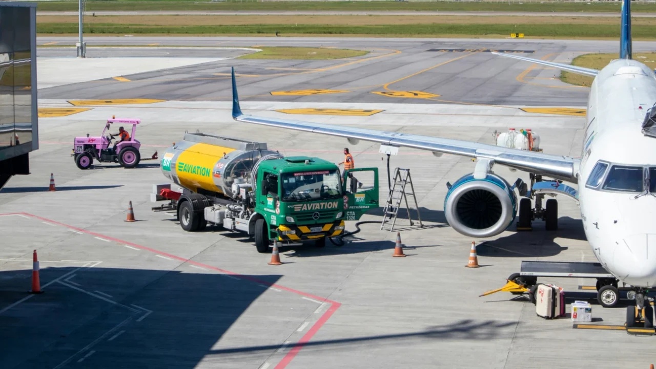 truk tangki berwarna hijau kuning yang membawa bahan bakar pesawat di bandara pada siang hari