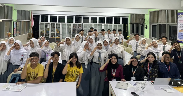 sekumpulan anak berseragam SMA dan delapan orang berbaju bebas berpose menghadap kamera di dalam ruang kelas