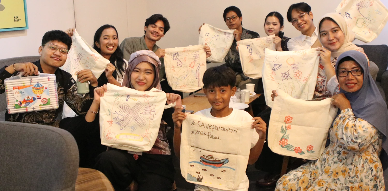 sepuluh orang muda berpose menghadap kamera sambil membawa tote bag yang telah dihias