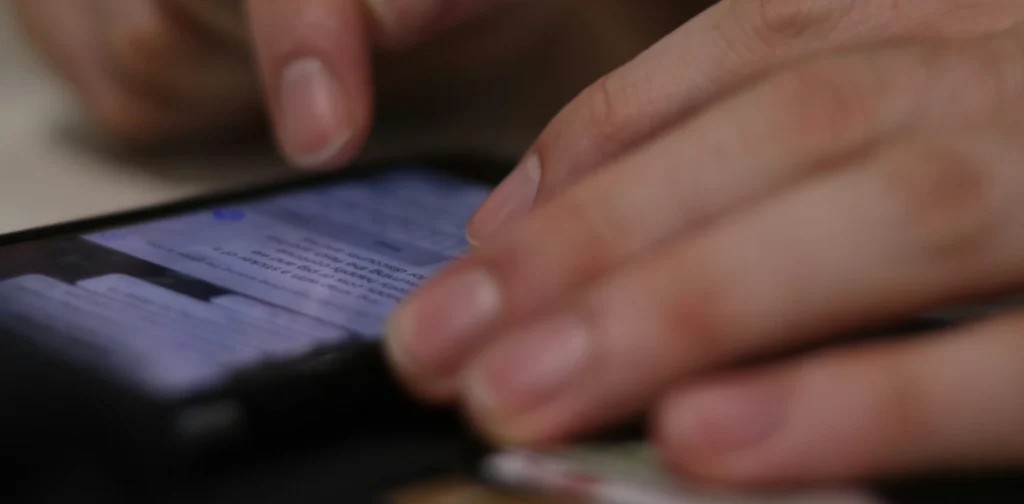 sepasang tangan sedang mengetik di layar ponsel