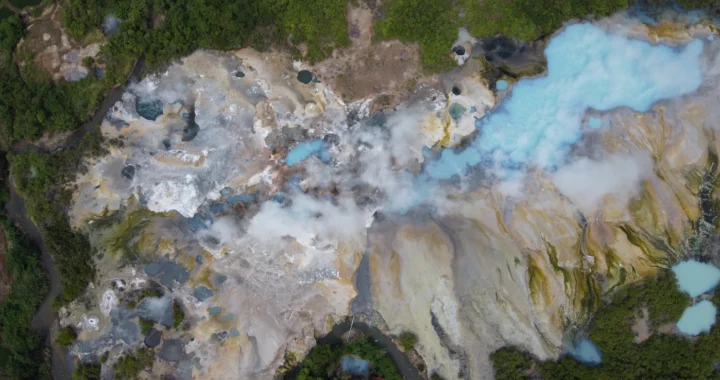 Foto udara salah satu kawasan geothermal di Suoh, Taman Nasional Bukit Barisan Selatan (TNBBS). Menampilkan kawah beruap dengan kolam air berwarna biru dan putih, dikelilingi vegetasi hijau di sekitarnya.