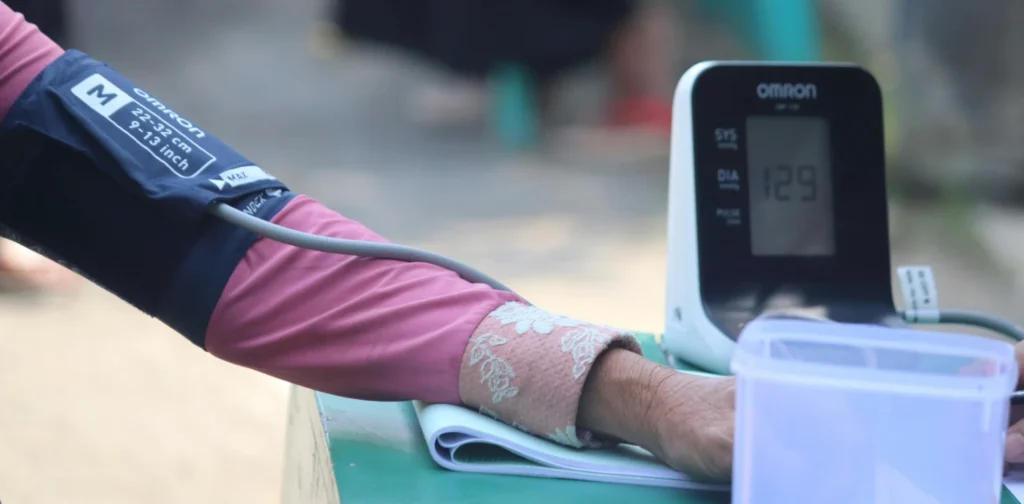 sebuah lengan berbaju pink sedang menjalani pemeriksaan tensi dengan alat