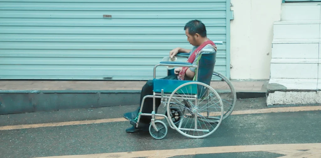 seorang pria duduk di kursi roda di depan sebuah toko yang tutup