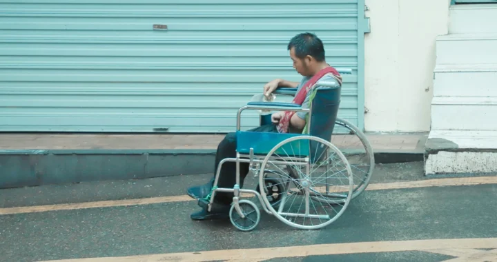 seorang pria duduk di kursi roda di depan sebuah toko yang tutup
