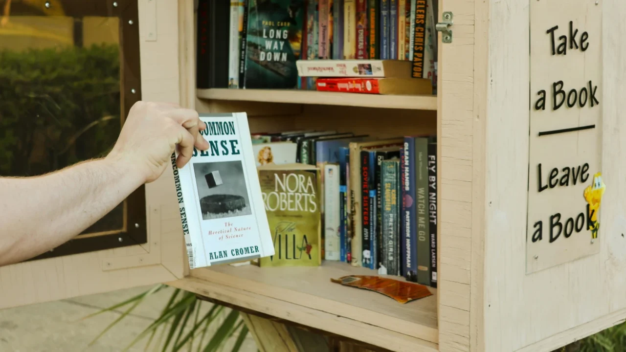 Seseorang sedang mengambil sebuah buku dari rak kecil