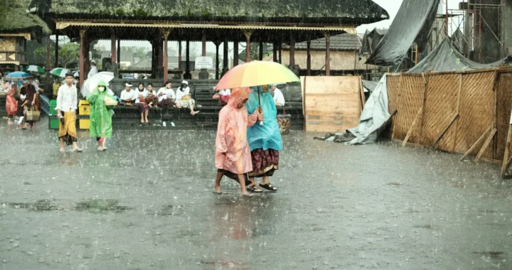 orang-orang mengenakan jas hujan dan memegang payung berjalan di tengah hujan