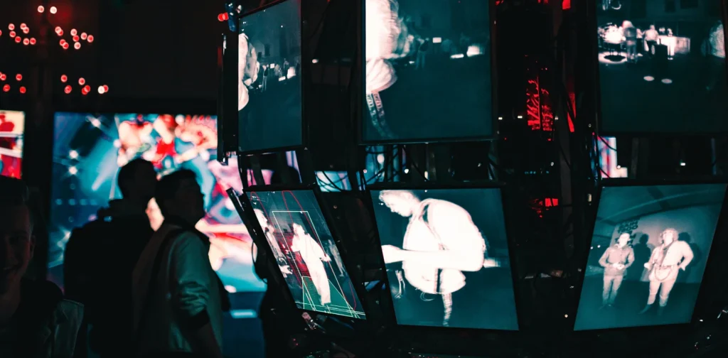 beberapa orang berdiri di sekitar deretan layar video