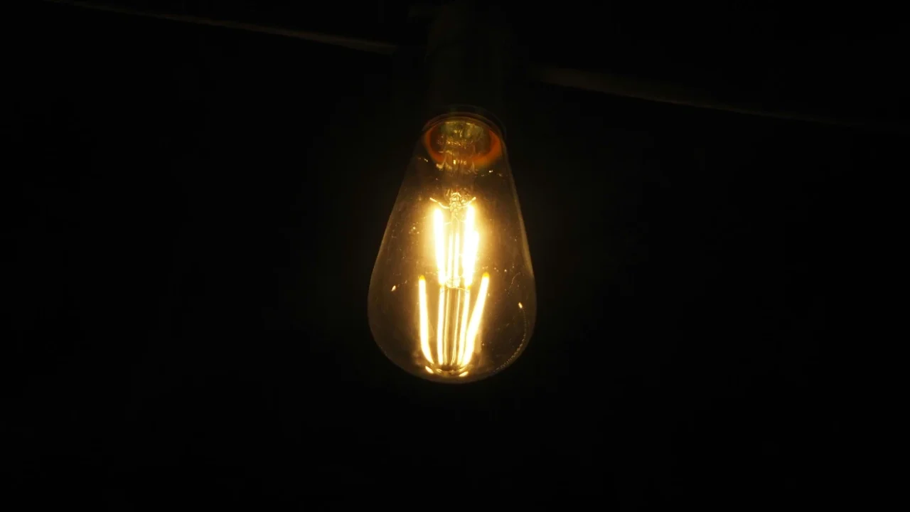 sebuah bola lampu di kegelapan dengan lampu berwarna kuning di dalamnya