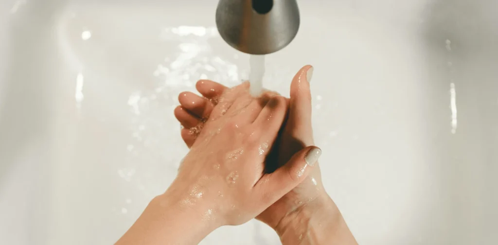 Seseorang mencuci tangan di wastafel.