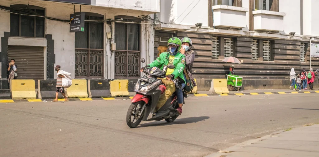 dua orang berkendara dengan sepeda motor.