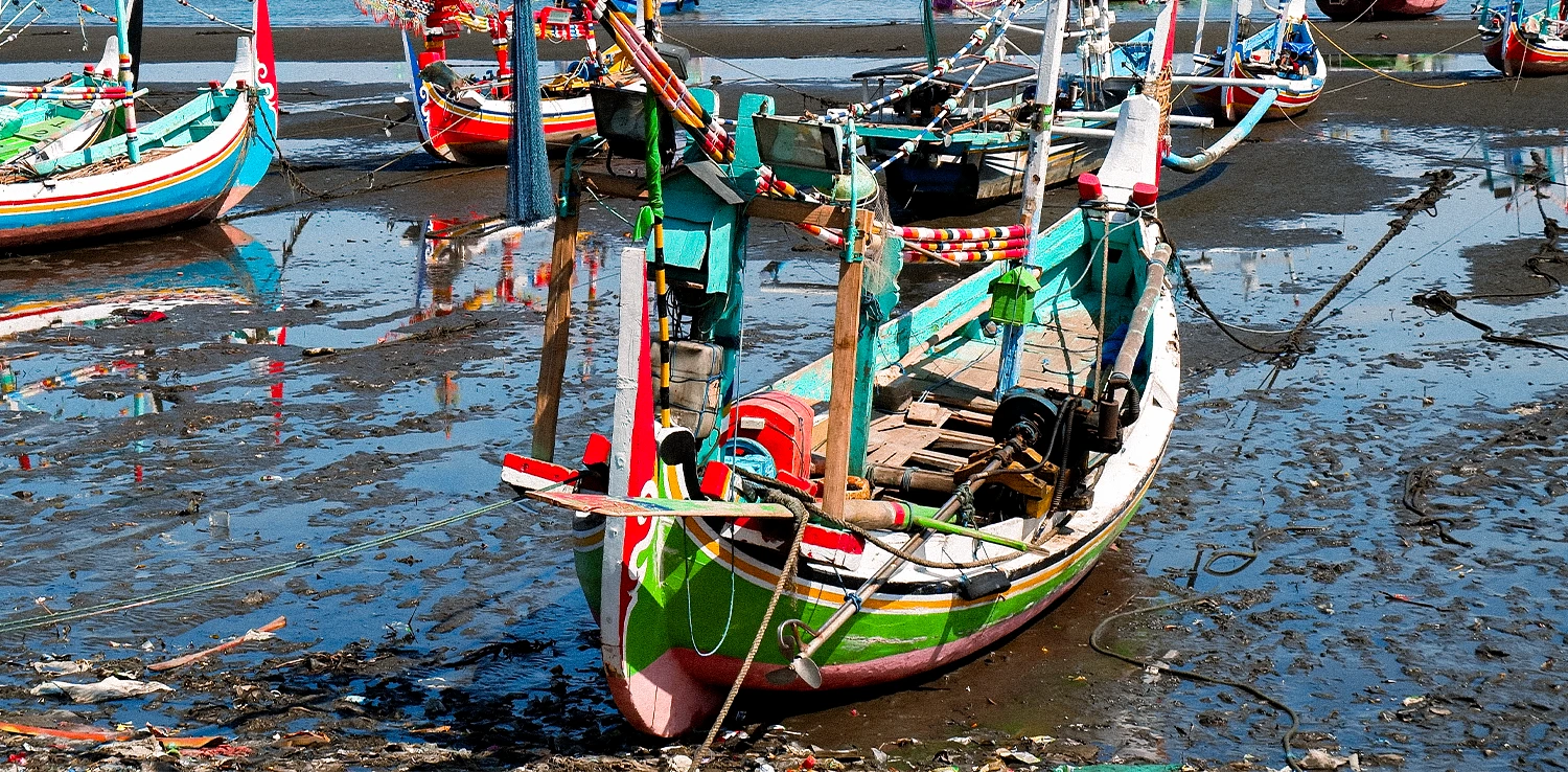 beberapa kapal kecil berlabuh di tepi pantai yang surut