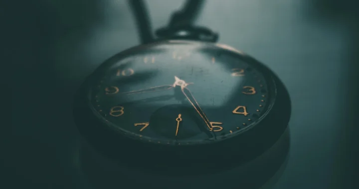 sebuah jam kantong berwarna hitam dengan angka berwarna emas di atas meja