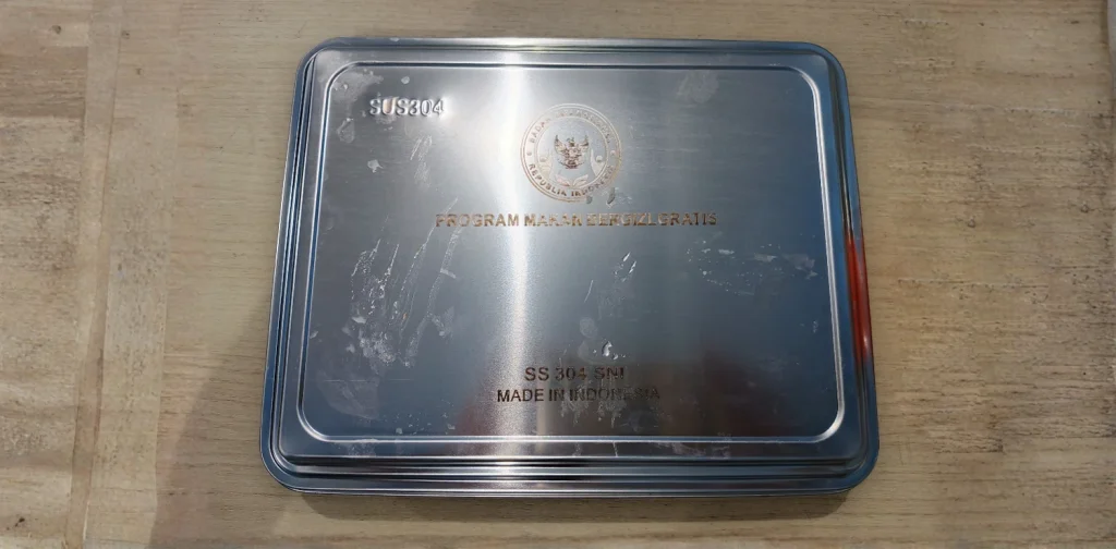 ompreng kaleng bertuliskan ‘program makan bergizi gratis’.