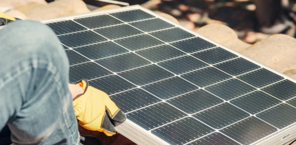 tangan sedang memasang panel surya di atap