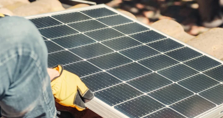 tangan sedang memasang panel surya di atap