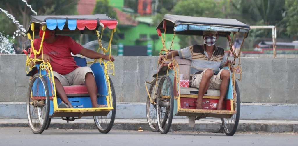 dua pria masing-masing duduk di atas becak sepeda.