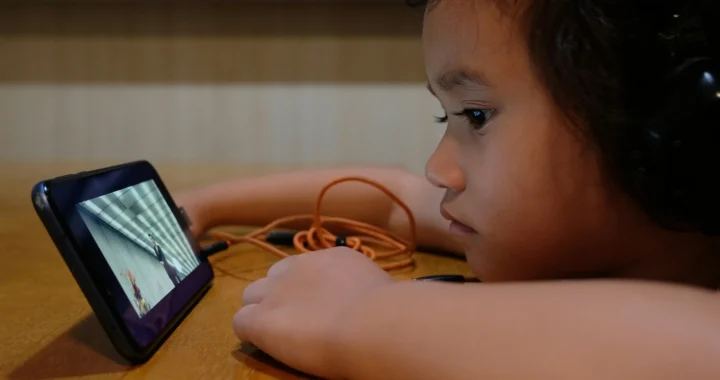 seorang anak dengan headset menatap layar ponsel