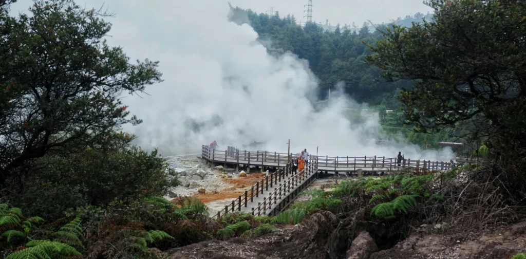alan setapak dari kayu dikelilingi asap panas bumi