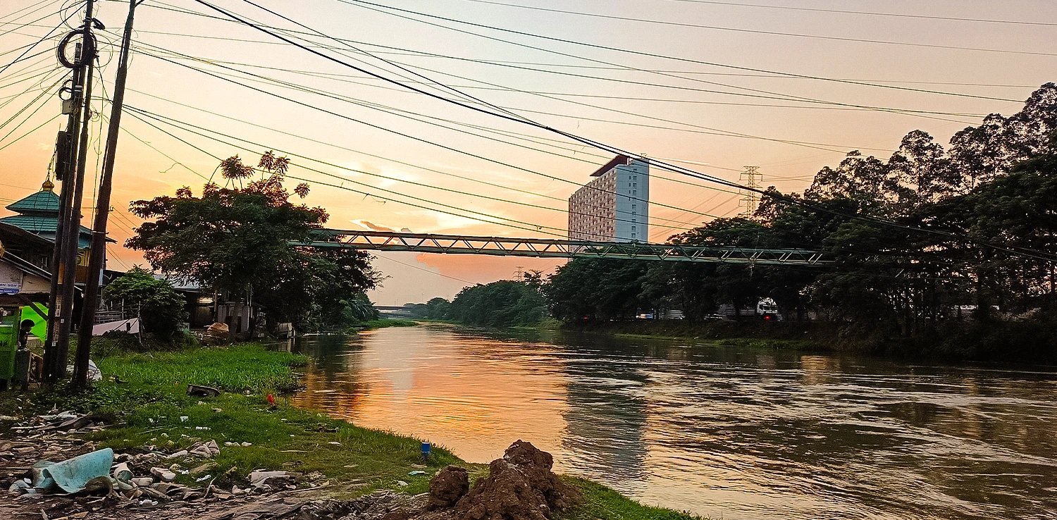 badan air berwarna kecoklatan dengan latar bangunan gedung tinggi