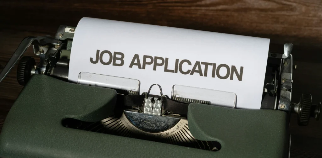 mesin tik dengan kertas putih bertuliskan ‘job application’