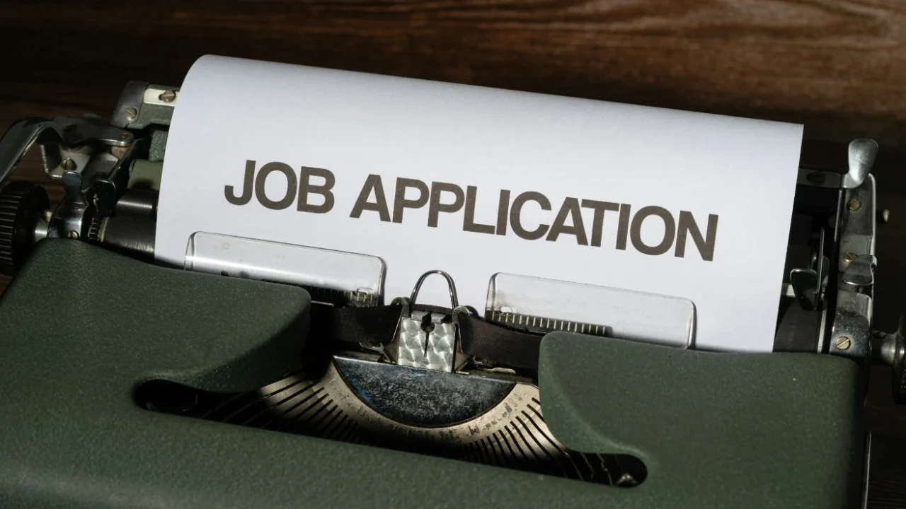 mesin tik dengan kertas putih bertuliskan ‘job application’