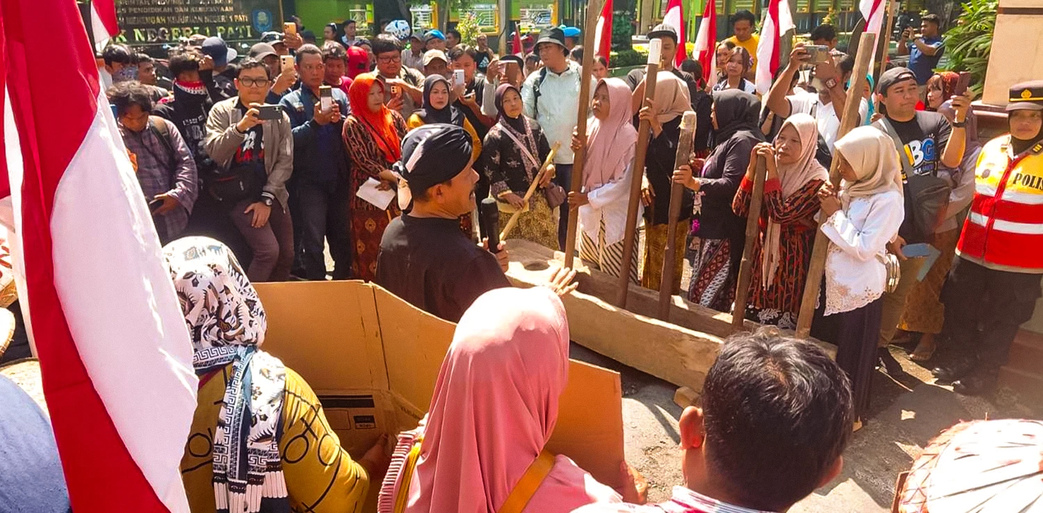 beberapa perempuan menabuh lesung padi dikelilingi banyak orang yang sebagian memotret dengan kamera ponsel.