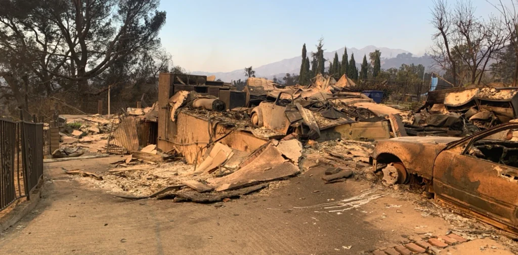 Sebuah rumah yang hangus dan kendaraan yang hancur akibat Kebakaran Eaton di California, 2025.