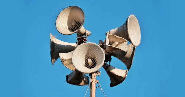 Foto jarak dekat beberapa megaphone tua pada sebuah tiang dengan latar belakang langit biru cerah