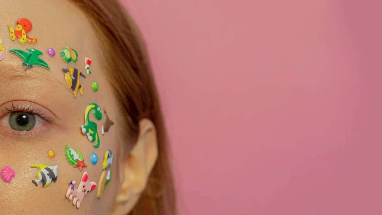 foto close-up separuh wajah seorang perempuan yang ditempeli stiker-stiker kecil