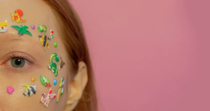 foto close-up separuh wajah seorang perempuan yang ditempeli stiker-stiker kecil